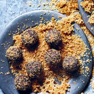 Two gray plates filled with golden bourboninfused sugar topped with dark chocolate truffles that have been coated in...