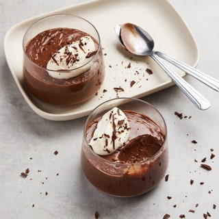 Two servings of chocolate pudding topped with whipped cream and shaved chocolate.