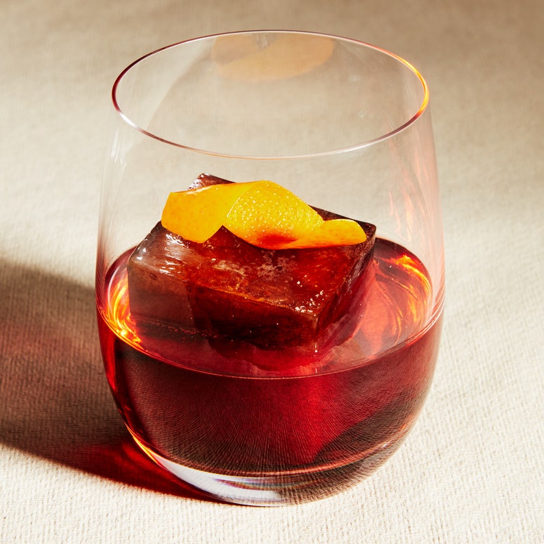 A coffee negroni in a glass garnished with an orange peel