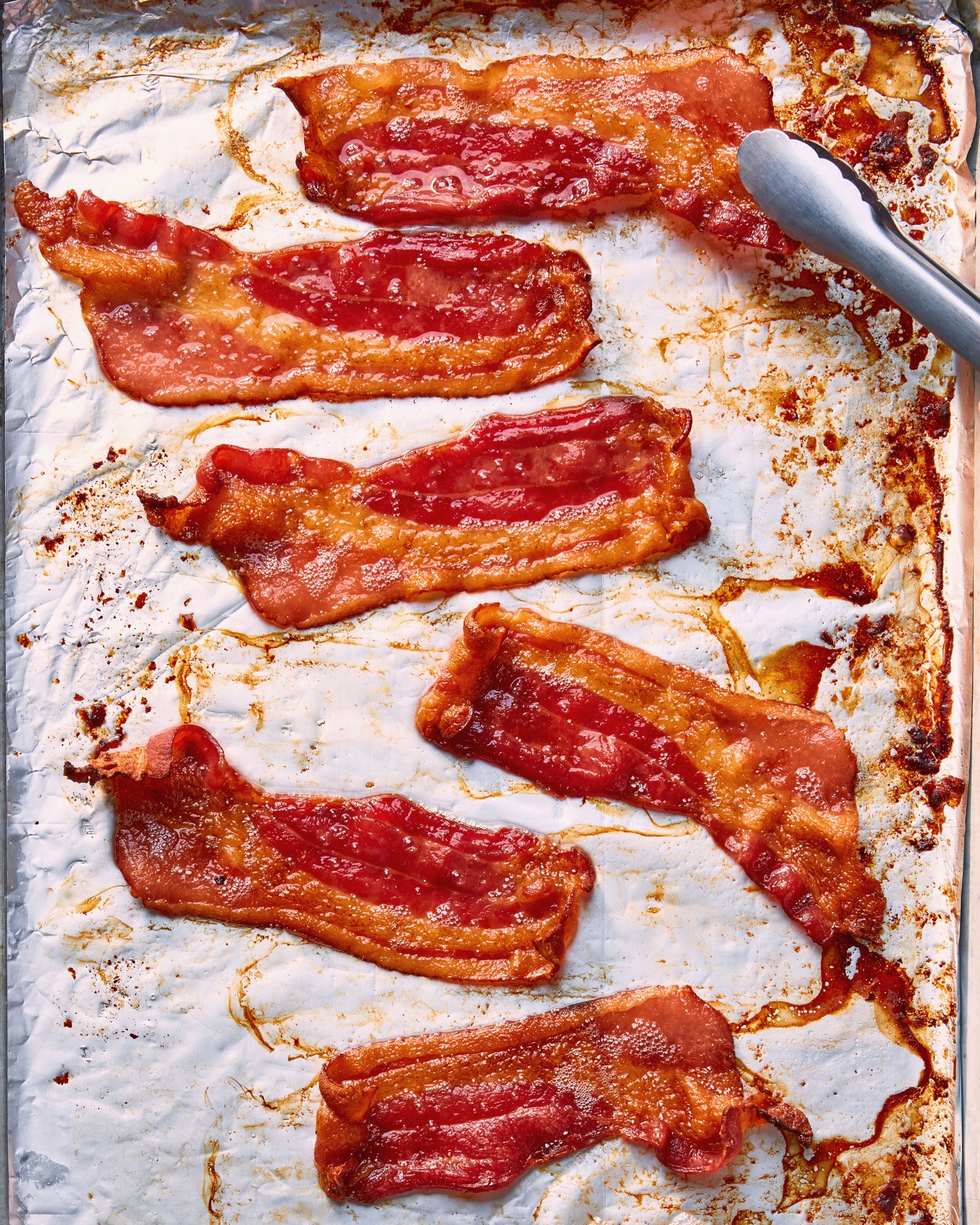 Strips of crispy bacon on a sheet of aluminum foil.