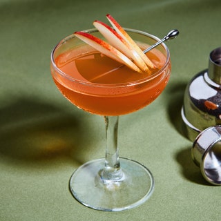 A Jack Rose in a coupe garnished with three apple slices.
