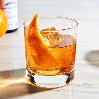 An old fashioned cocktail in a rocks glass garnished with a strip of orange peel.