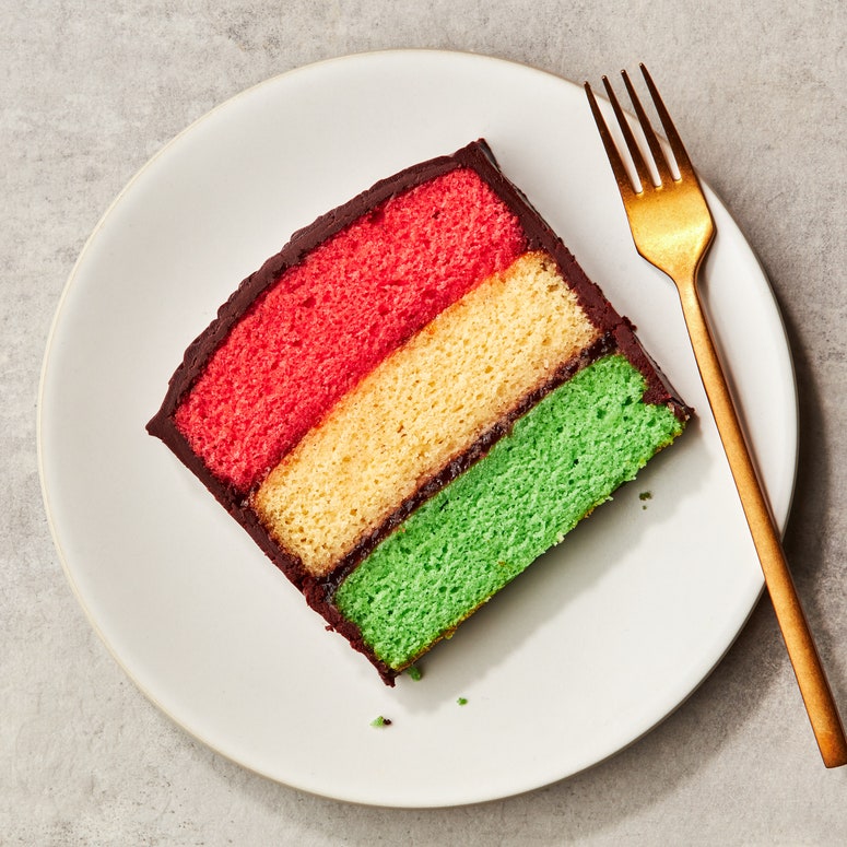 A single slice of a rainbow cookie cake on a plate.