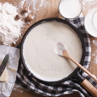 White sauce recipe in a pan with flour and butter on the side.