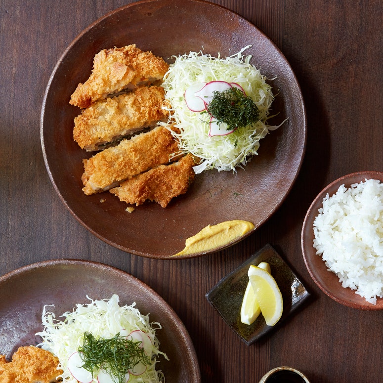 Tonkatsu on two plates with shredded cabbage.