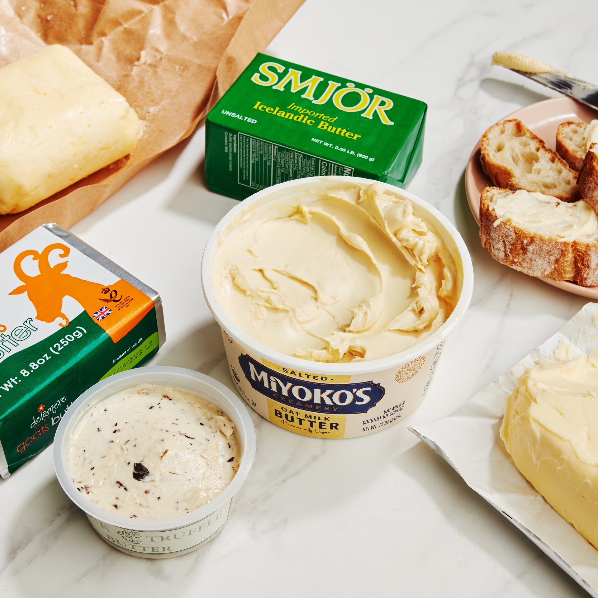 A variety of different types of butter on a counter with toast.